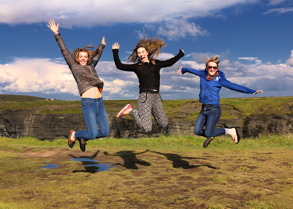 three young ladies from Northern Ireland jumping in the air at the Bridges of Ross in County Clare